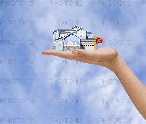 Hand of woman holding home for sale in sky