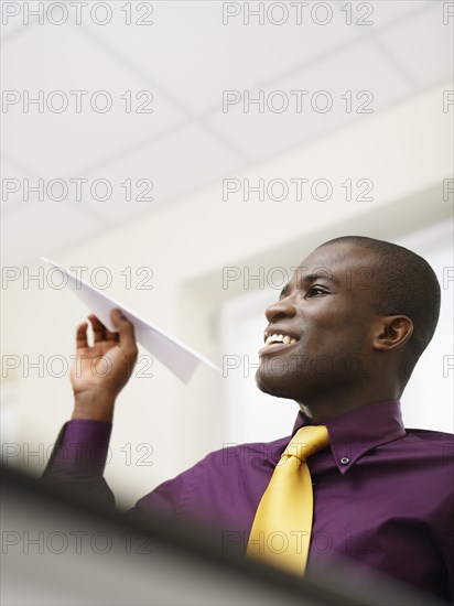 Black businessman throwing paper airplane