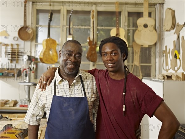 Black craftsman in guitar workshop with son