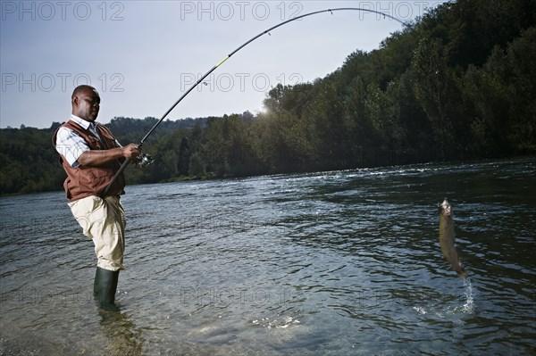 Black man catching fish in stream