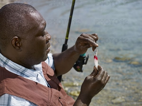 Black man putting lure on fishing pole