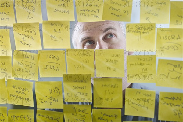 Caucasian businessman looking at adhesive notes on wall