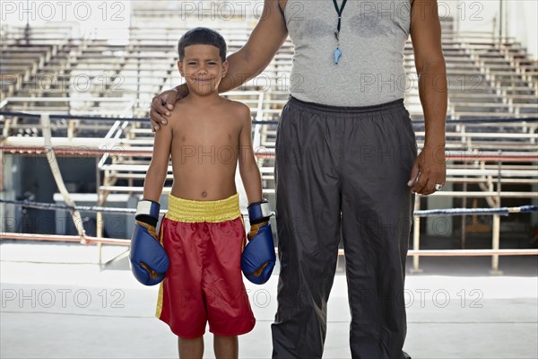 Hispanic trainer standing with boy in boxing gear
