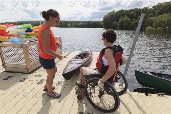 Caucasian instructor helping paraplegic woman with kayak