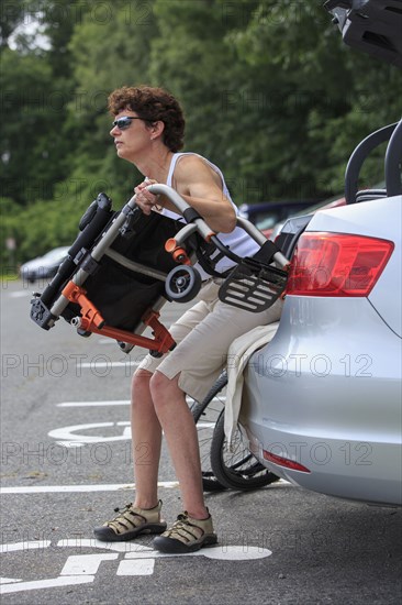 Caucasian paraplegic woman unloading wheelchair from car