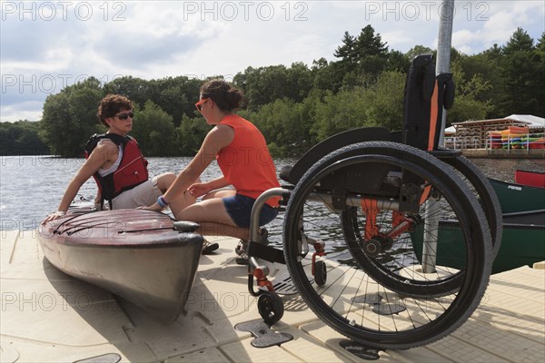 Caucasian instructor helping paraplegic woman with kayak