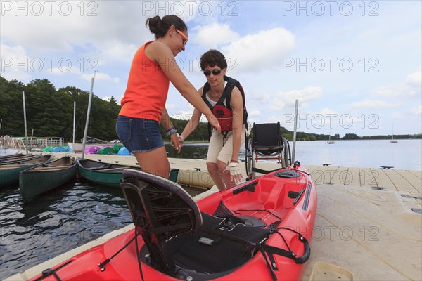 Caucasian instructor helping paraplegic woman with kayak