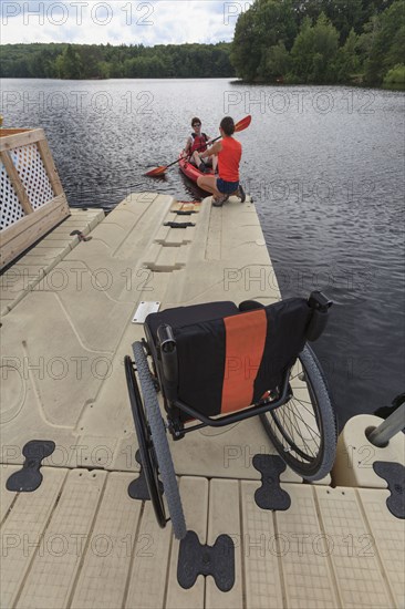 Caucasian instructor helping paraplegic woman with kayak