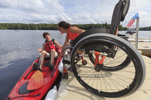 Caucasian instructor helping paraplegic woman with kayak