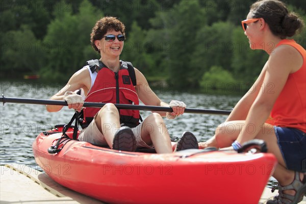 Caucasian instructor helping paraplegic woman with kayak