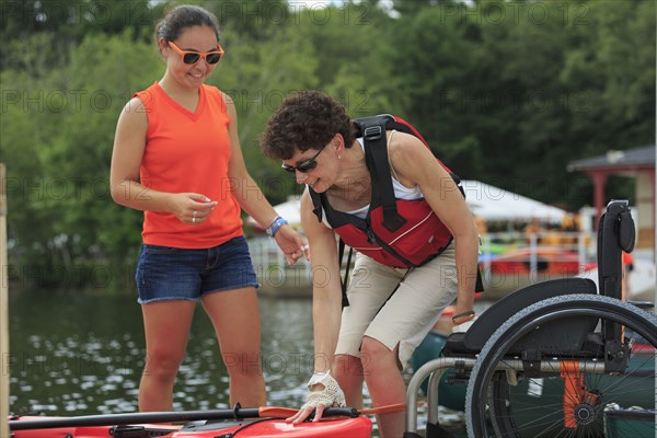 Caucasian instructor helping paraplegic woman with kayak