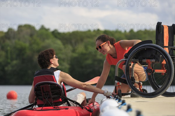 Caucasian instructor helping paraplegic woman with kayak