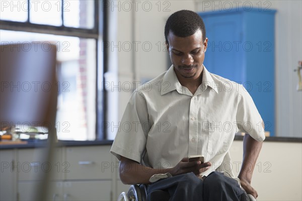 African American paraplegic man using cell phone