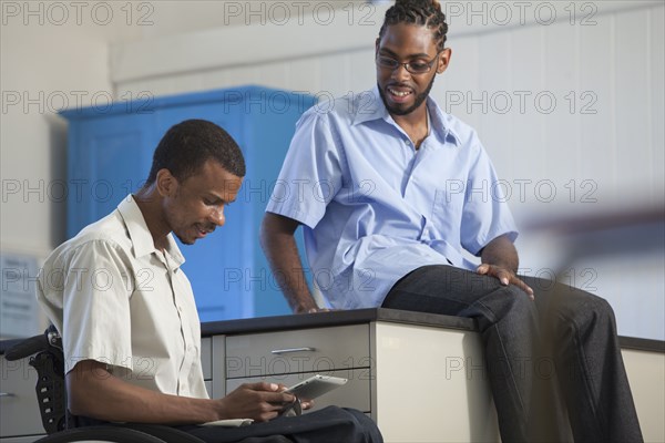 Paraplegic student and classmate using digital tablet