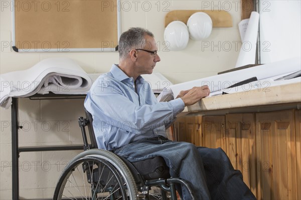 Caucasian architect in wheelchair working in office