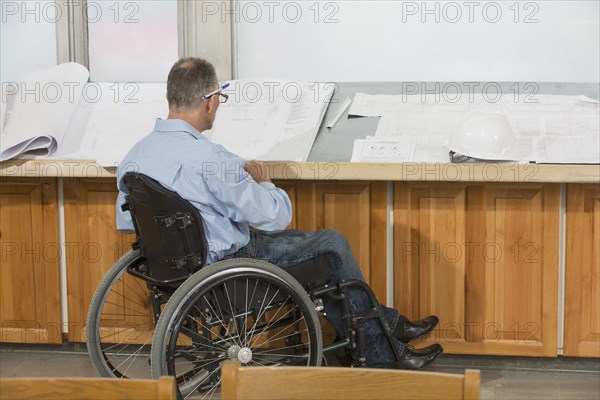 Caucasian architect in wheelchair talking in office