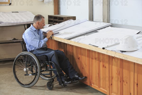 Caucasian architect in wheelchair working in office