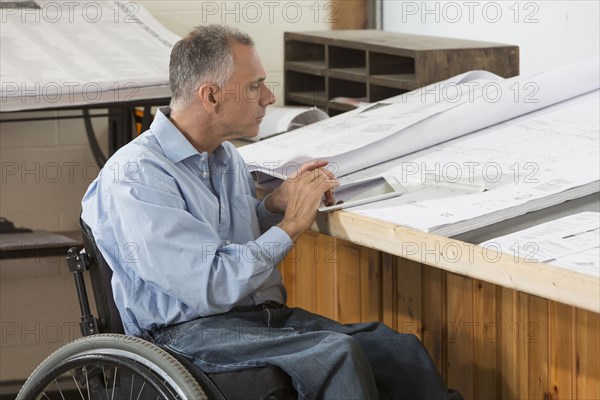 Caucasian architect in wheelchair working in office