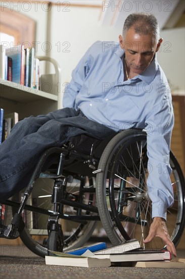 Caucasian man picking up books in library