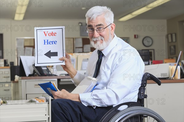 Caucasian businessman holding voting sign in office