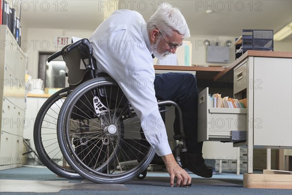 Caucasian businessman picking up object on floor