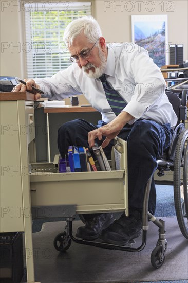 Caucasian businessman filing papers at desk