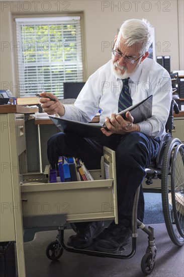 Caucasian businessman reading binder at desk