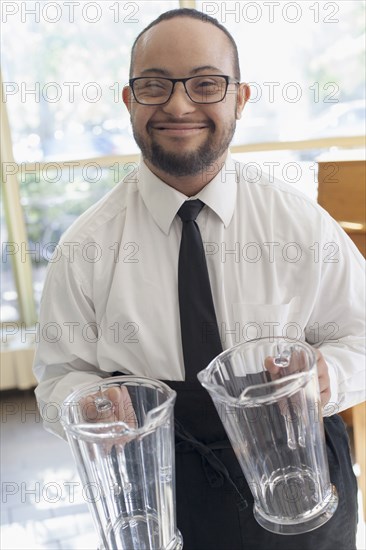 Mixed race server with down syndrome holding pitchers in restaurant