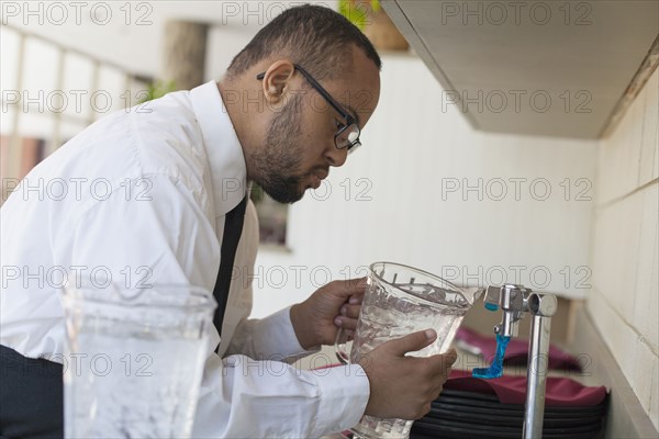 Mixed race server with down syndrome filling pitcher in restaurant