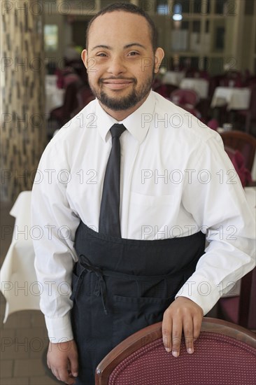 Mixed race server with down syndrome smiling in restaurant