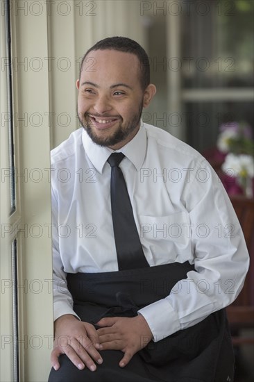 Mixed race server with down syndrome smiling in restaurant