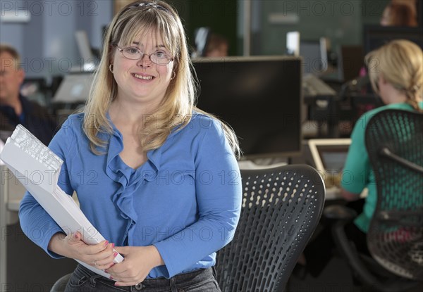 Caucasian businesswoman with Down Syndrome smiling in office