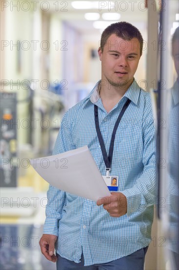 Caucasian man with Down Syndrome holding paperwork in hospital