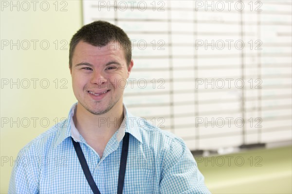 Caucasian man with Down Syndrome smiling in office