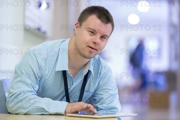 Caucasian man with Down Syndrome using digital tablet in hospital