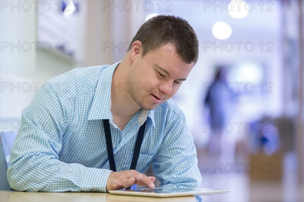 Caucasian man with Down Syndrome using digital tablet in hospital