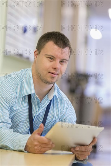 Caucasian man with Down Syndrome using digital tablet in hospital