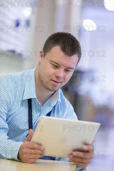 Caucasian man with Down Syndrome using digital tablet in hospital