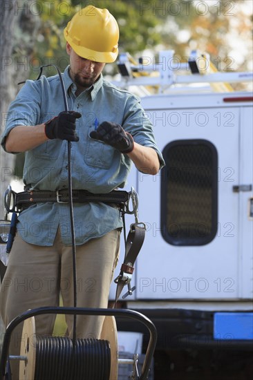 Caucasian worker unrolling cable spool