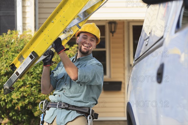 Caucasian worker carrying ladder