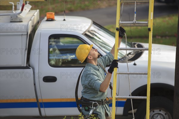 Caucasian worker raising ladder outdoors