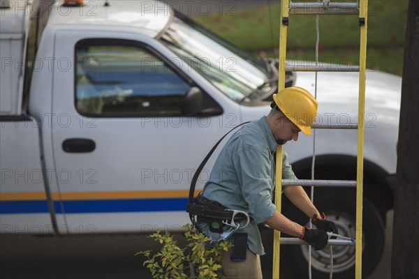 Caucasian worker raising ladder outdoors