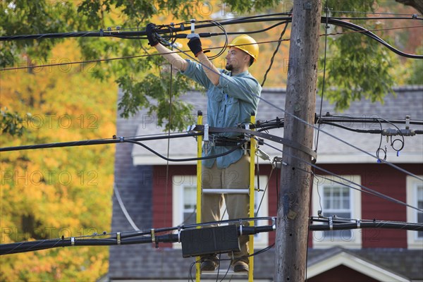 Caucasian cable installer working on ladder