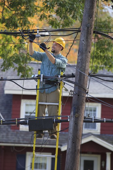 Caucasian cable installer working on ladder