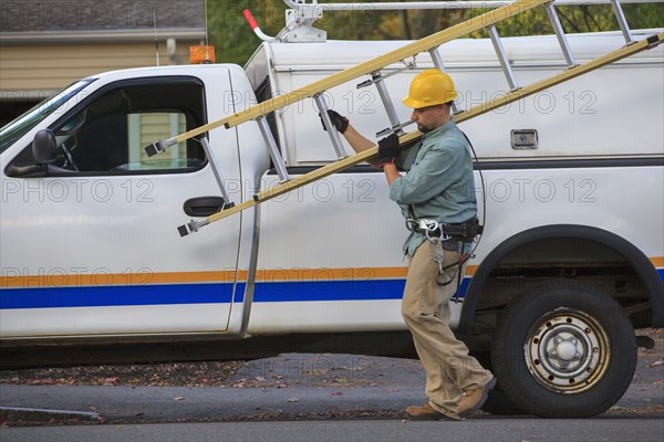 Caucasian worker carrying ladder near truck