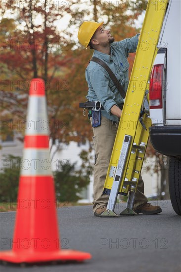 Caucasian worker loading ladder on truck