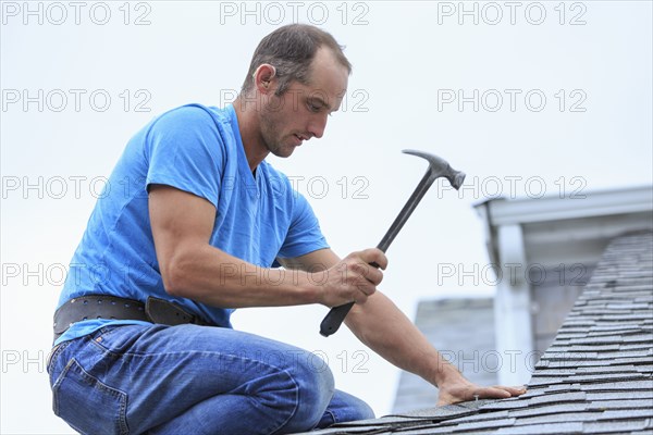 Deaf Caucasian roofer hammering on roof