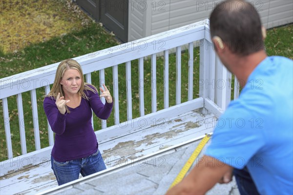 Caucasian homeowner signing to deaf roofer