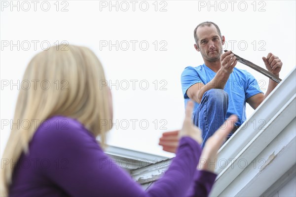 Caucasian homeowner signing to deaf roofer