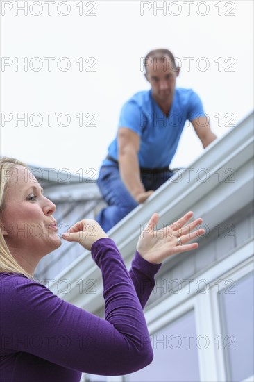 Caucasian homeowner signing to deaf roofer